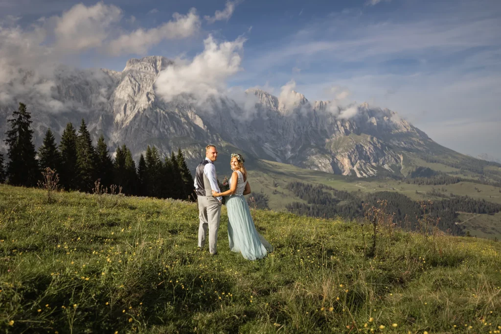 Freudiges Brautpaar bei der Trauung auf der Tiergartenalm, mit sonnigem Wetter und beeindruckender Bergkulisse.