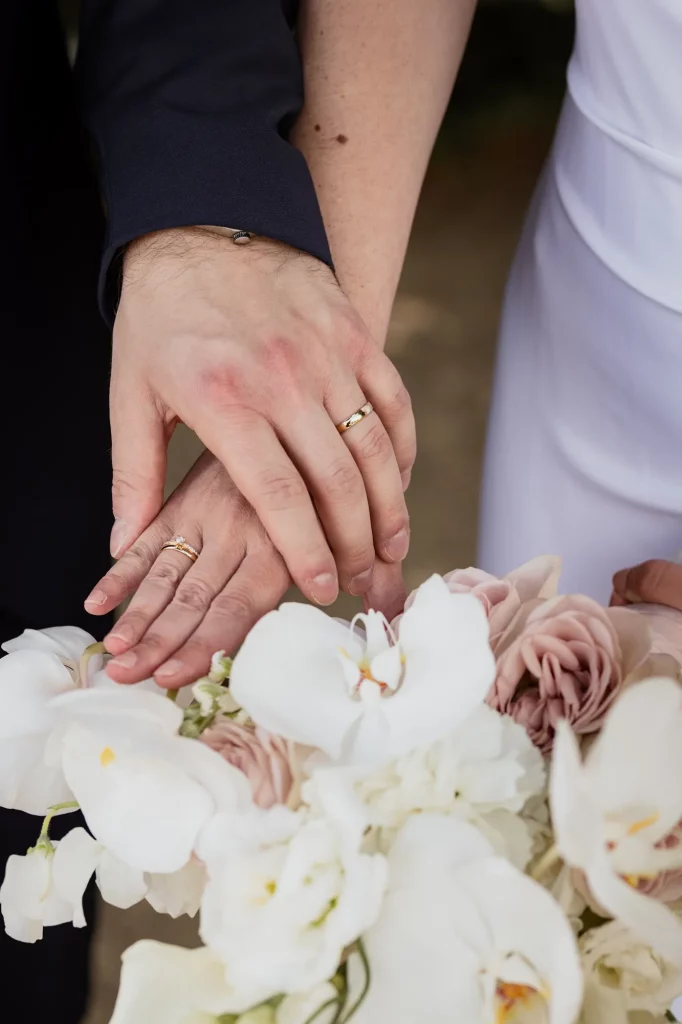 Brautpaar hält die Hand zum Hochzeitsstrauß, wunderschönes Detailbild von Brautpaarshooting, Hochzeitsfeier am Oberhaus Passau