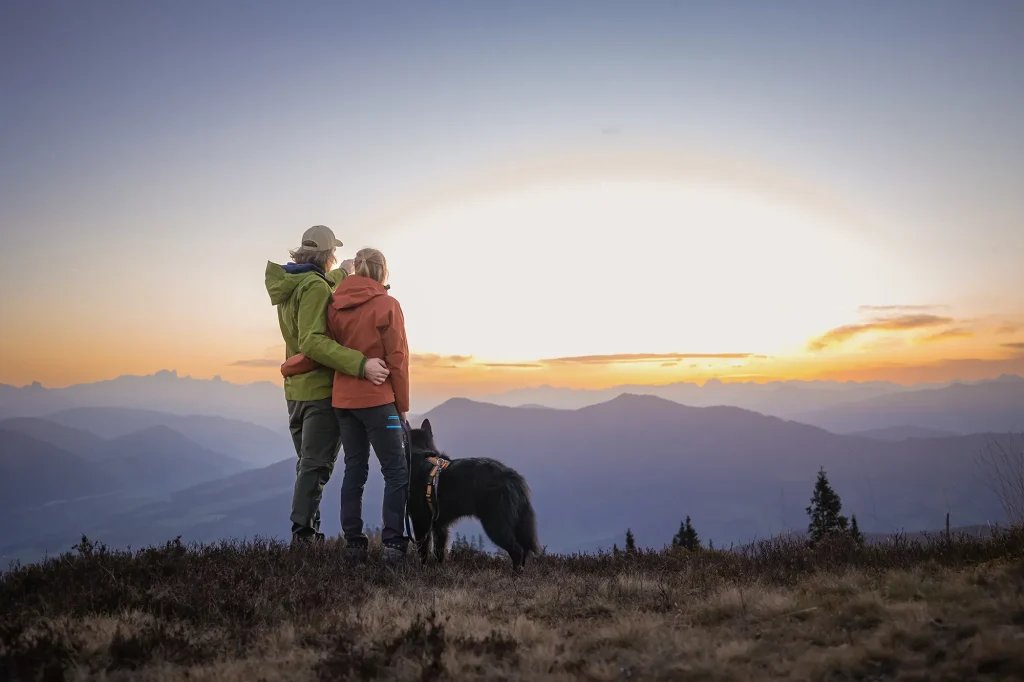 Glückliches Paar mit ihren Hund am Hochkeil zum Sonnenaufgang machen ein Fotoshooting