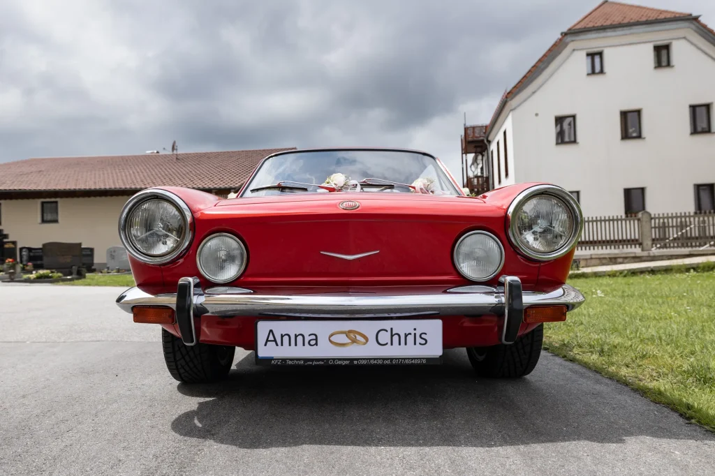 Sehr schönes Bild von roten Hochzeitsauto bei Hochzeit in Neukirchen vorm Wald. Heiraten in Niederbayern, Daniela Schmid Hochzeitsfotografie
