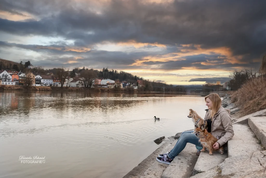 Wunderschönes Bild bei Sonnenaufgangsshooting von Mensch und Hund am Ufer des Flusses Inn.