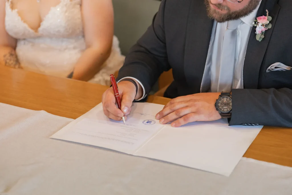 Bräutigam unterschreibt bei standesamtlicher Hochzeit in Neukirchen vorm Wald.