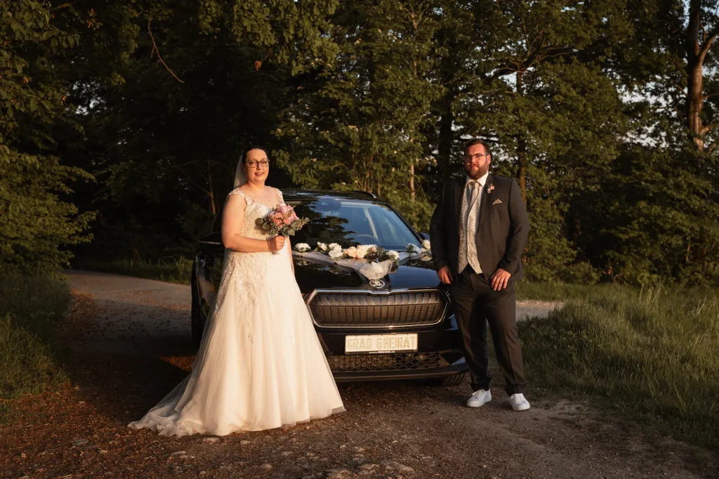 Ein sehr schönes Bild von Brautpaar zum Sonnenuntergang mit Brautauto in Neukirchen vorm Wald