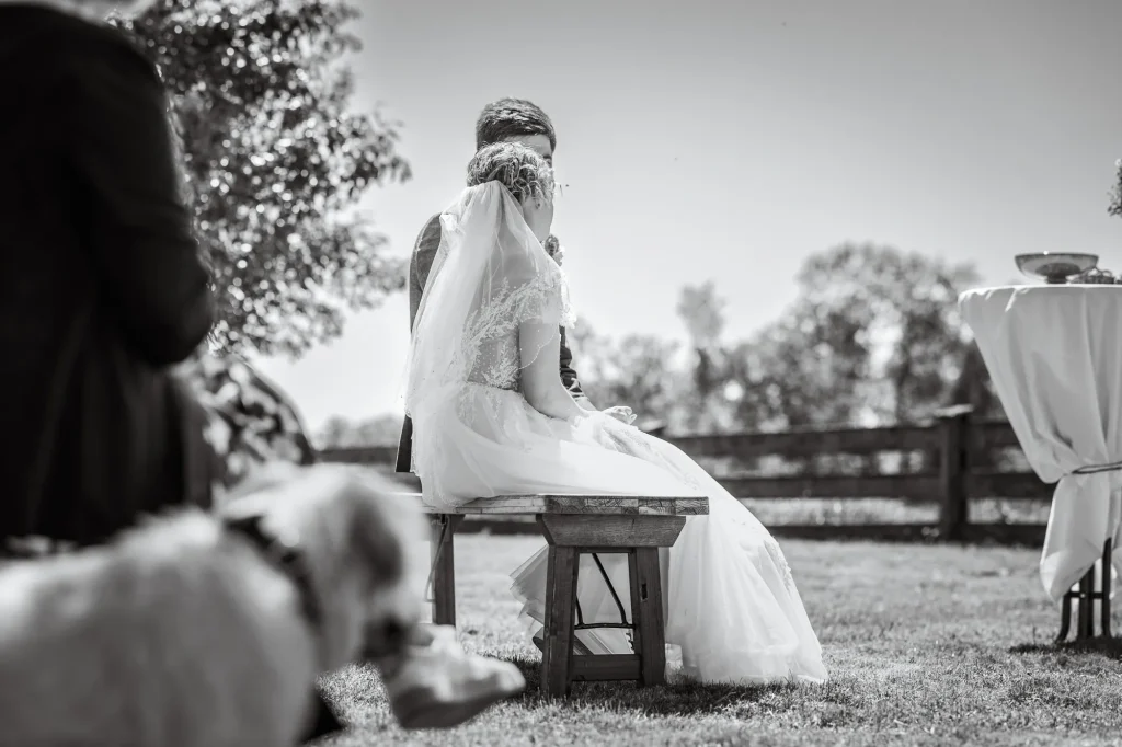 Ein wunderschönes Schwarz Weiß Bild zeigt das Brautpaar bei Hochzeitsfeier vorne sitzend während des großen Moments. Perfekte Hochzeitsreportage von Daniela Schmid Fotografie.